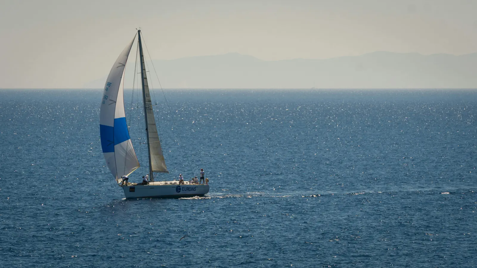 En segelbåt seglar förbi med endast försegel hissat